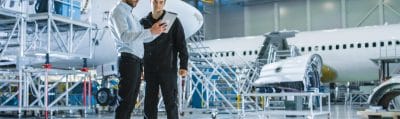 Aircraft maintenance worker and engineer reviewing work on a tablet