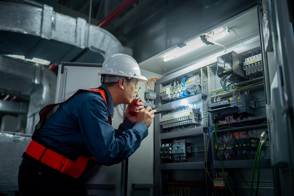 Industrial technicians working at a well-organised electrical control cabinet panel