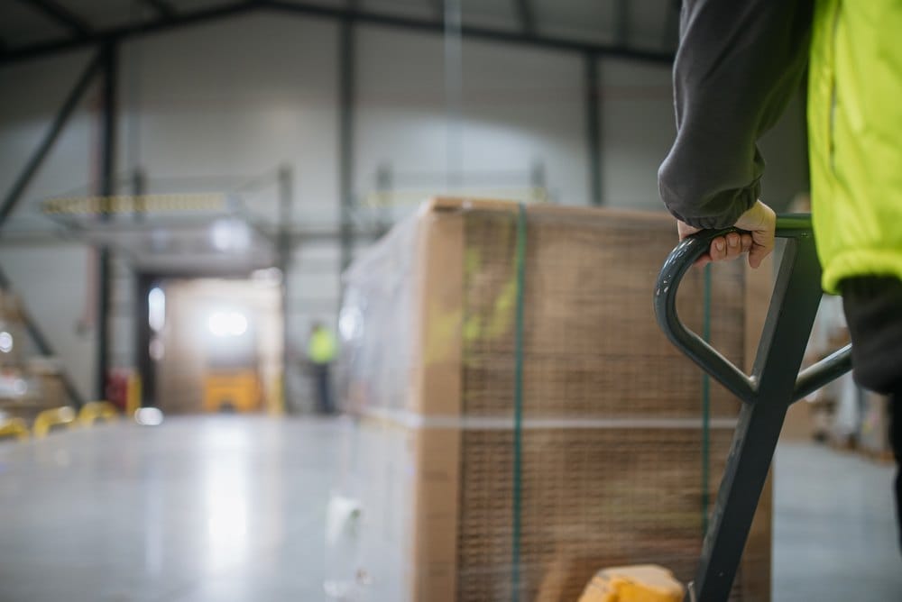 Warehouse worker moving a pallet jack loaded with goods