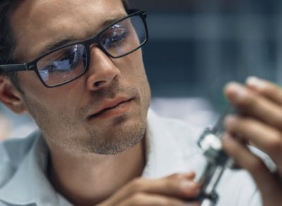 Engineer examining a manufactured metal part before production