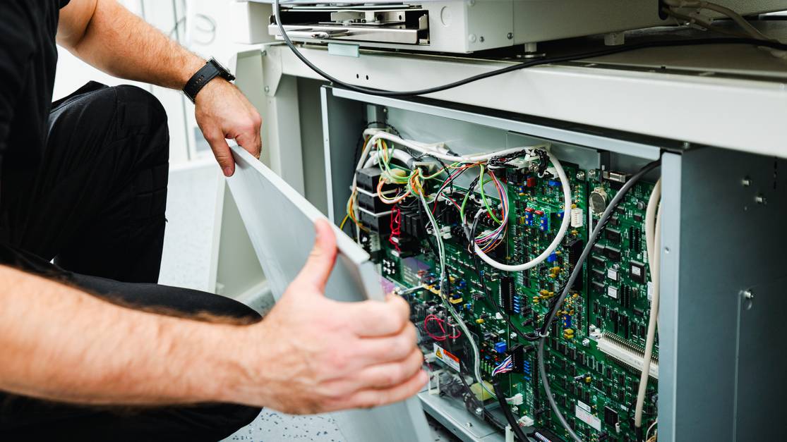 Engineer removing the cover of a medical X-ray unit for inspection during maintenance