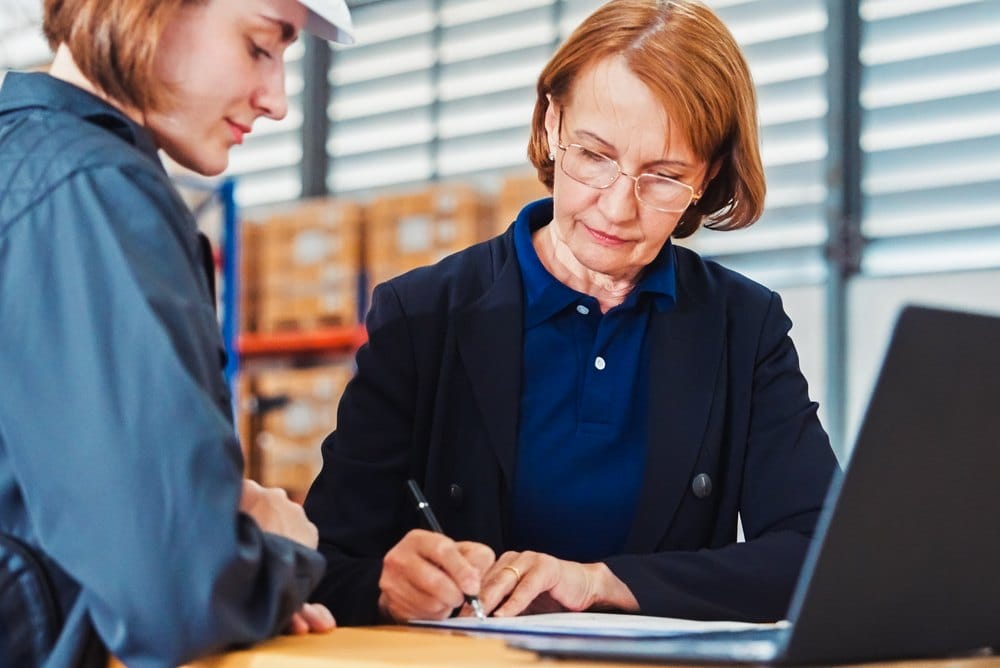 Manager signing an approval document in a distribution warehouse