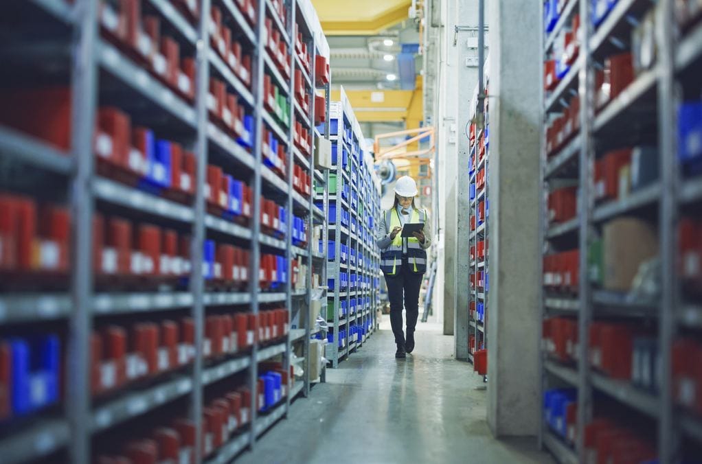 Maintenance stores manager checking inventory on a tablet in a warehouse aisle