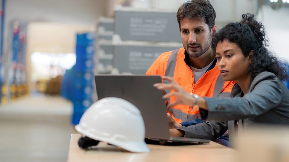 Warehouse manager and inventory controller reviewing supplier stock data together on a laptop
