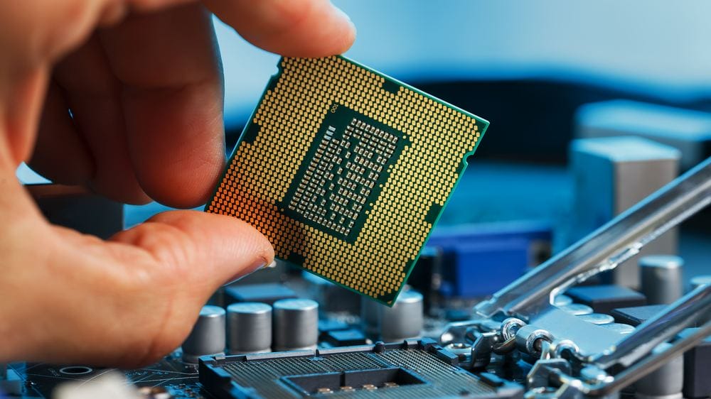Engineer inspecting a processor chip above a circuit board during incoming testing