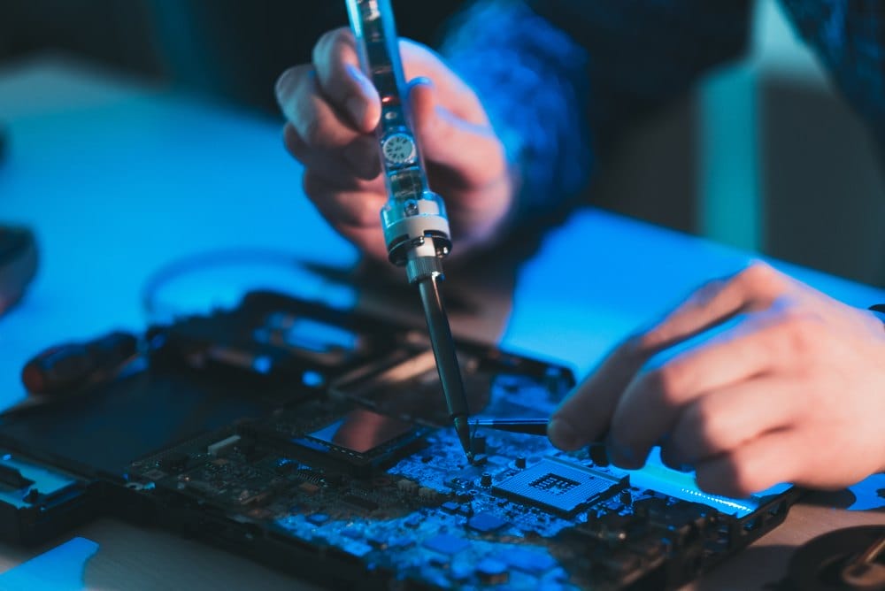 Technician soldering a component on an electronic circuit board during repair