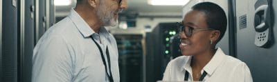 Technicians reviewing equipment on a tablet in a data centre aisle